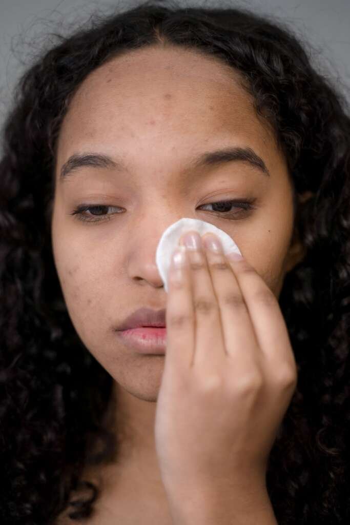 Woman gently cleansing her face with a cotton pad